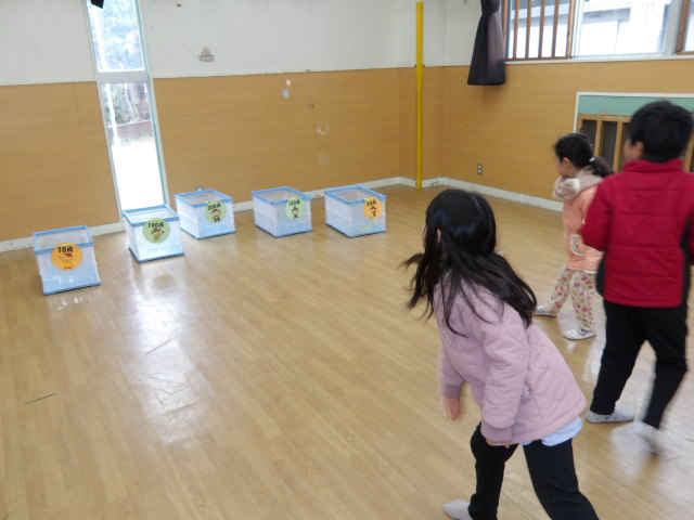 点数を付けた箱に頑張って紙飛行機を入れようとする小学生と幼児の写真