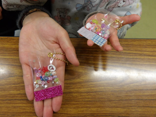 お母さんと幼児の手に乗せた完成したシャカキーホルダーの写真。