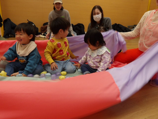 講師の動きを真似しながら、円になって歩く講師と幼児親子達の写真