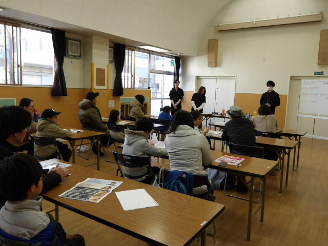 集会室にてフコク生命の社員さんからYouTubeの作り方の説明を受ける小学生親子達の写真