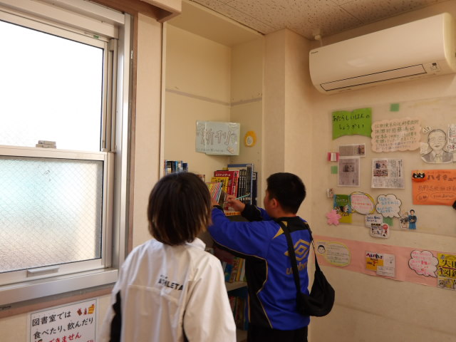 図書室に貼られた折り紙で作ったたまごに、書かれている文字を解答用紙に書く男子小学生2人の写真