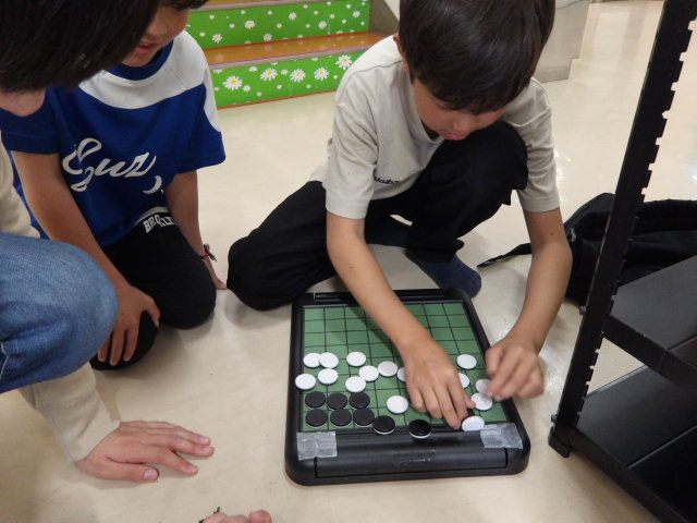 オセロひっくり返しゲームをする小学生の写真