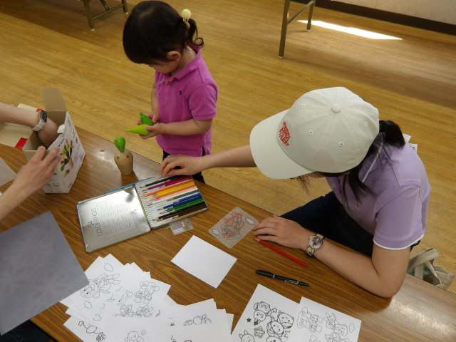 ボールプールに入ってママの読み聞かせを聞いている幼児の写真