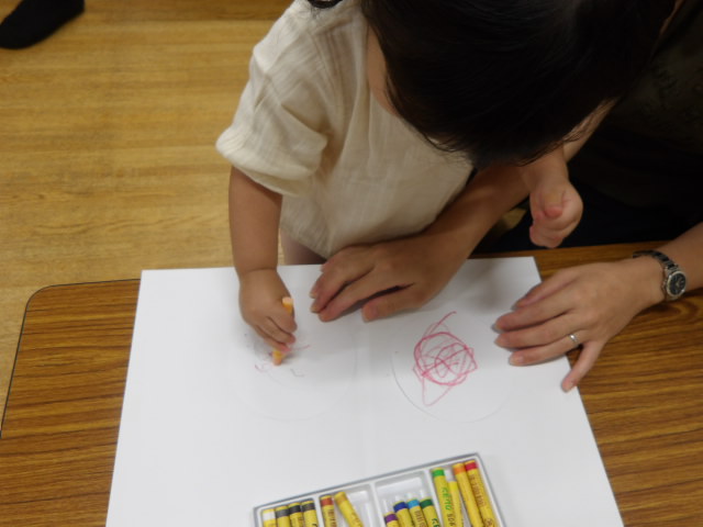 お母さんと一緒に工作をする幼児の写真