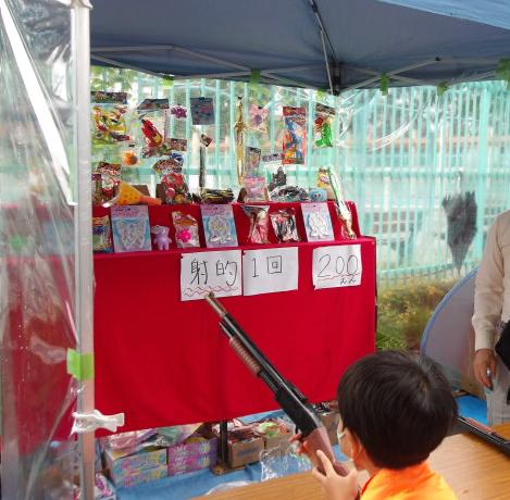 地域団体が出店している射的に挑戦する子どもの写真