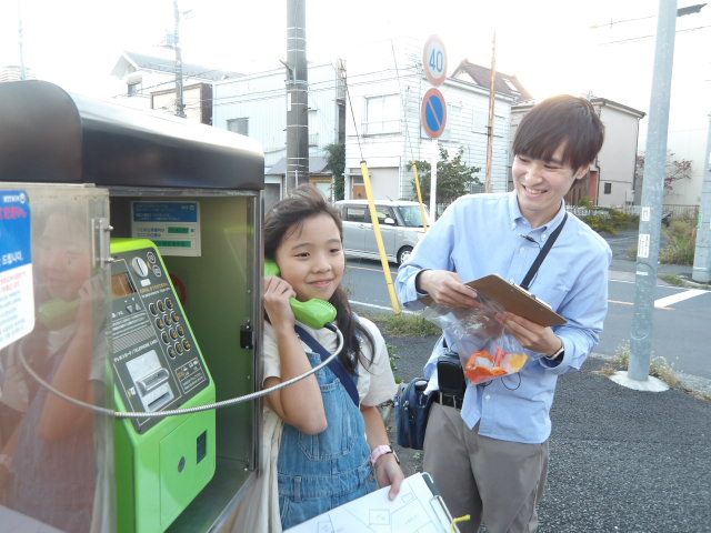 公衆電話をかける子供の写真