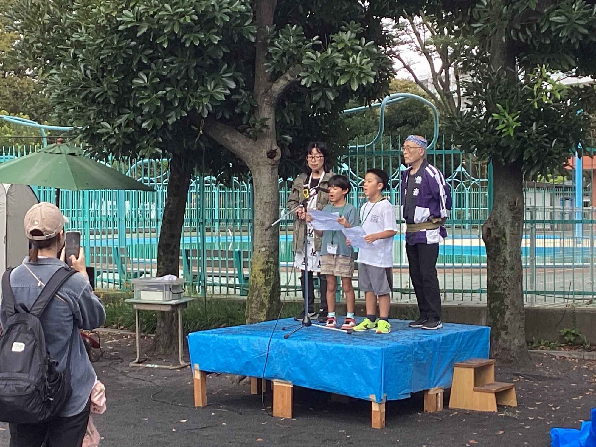 平間公園に設置された舞台で開会宣言をする子ども実行委員達の様子の写真
