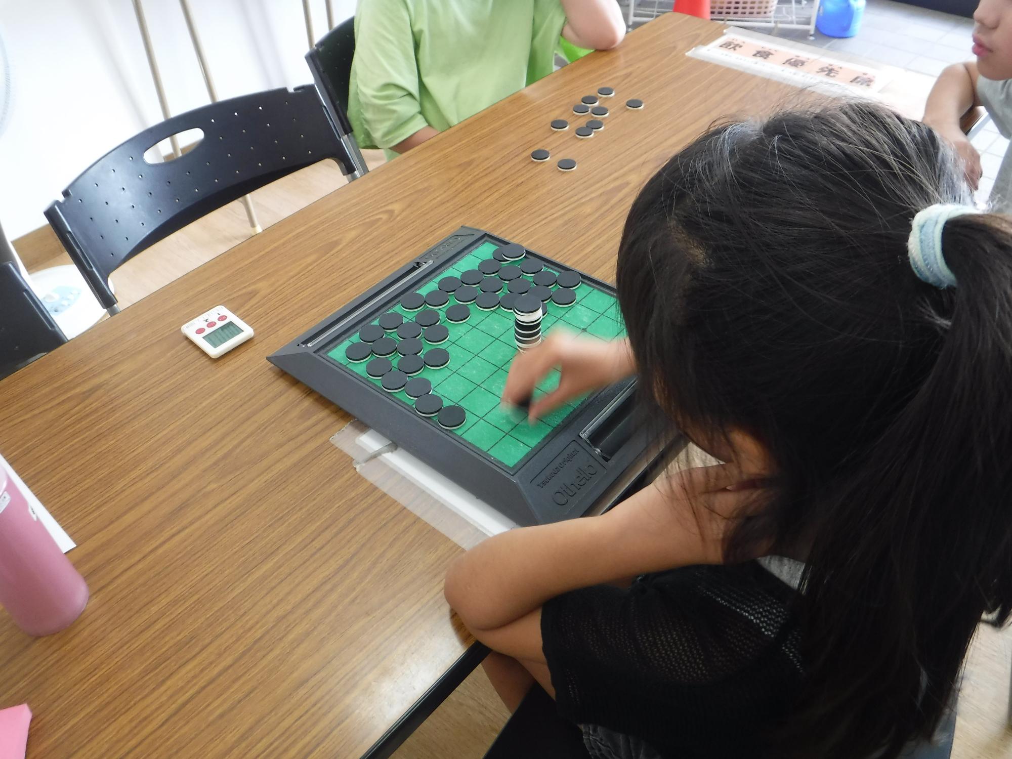 オセロの板にオセロタワーをしている子の写真