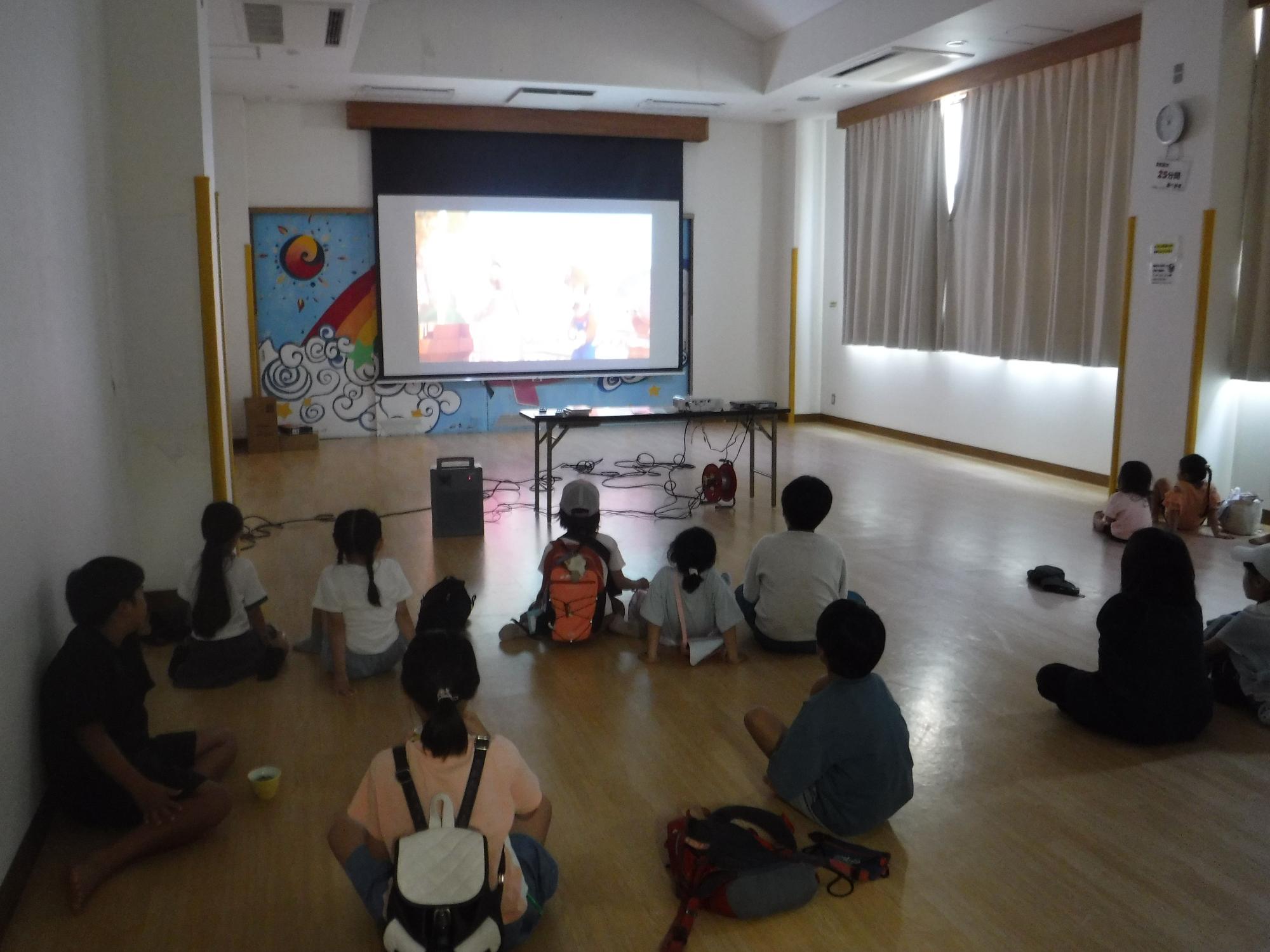 こども達が集会室で映画を観ている写真