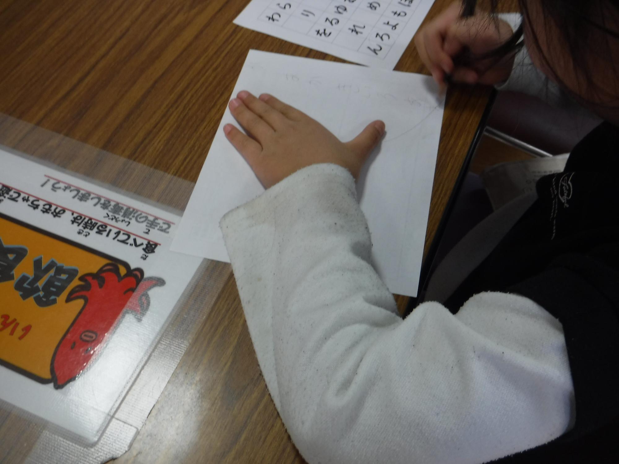 あいうえお表から考えて文字を書いている写真