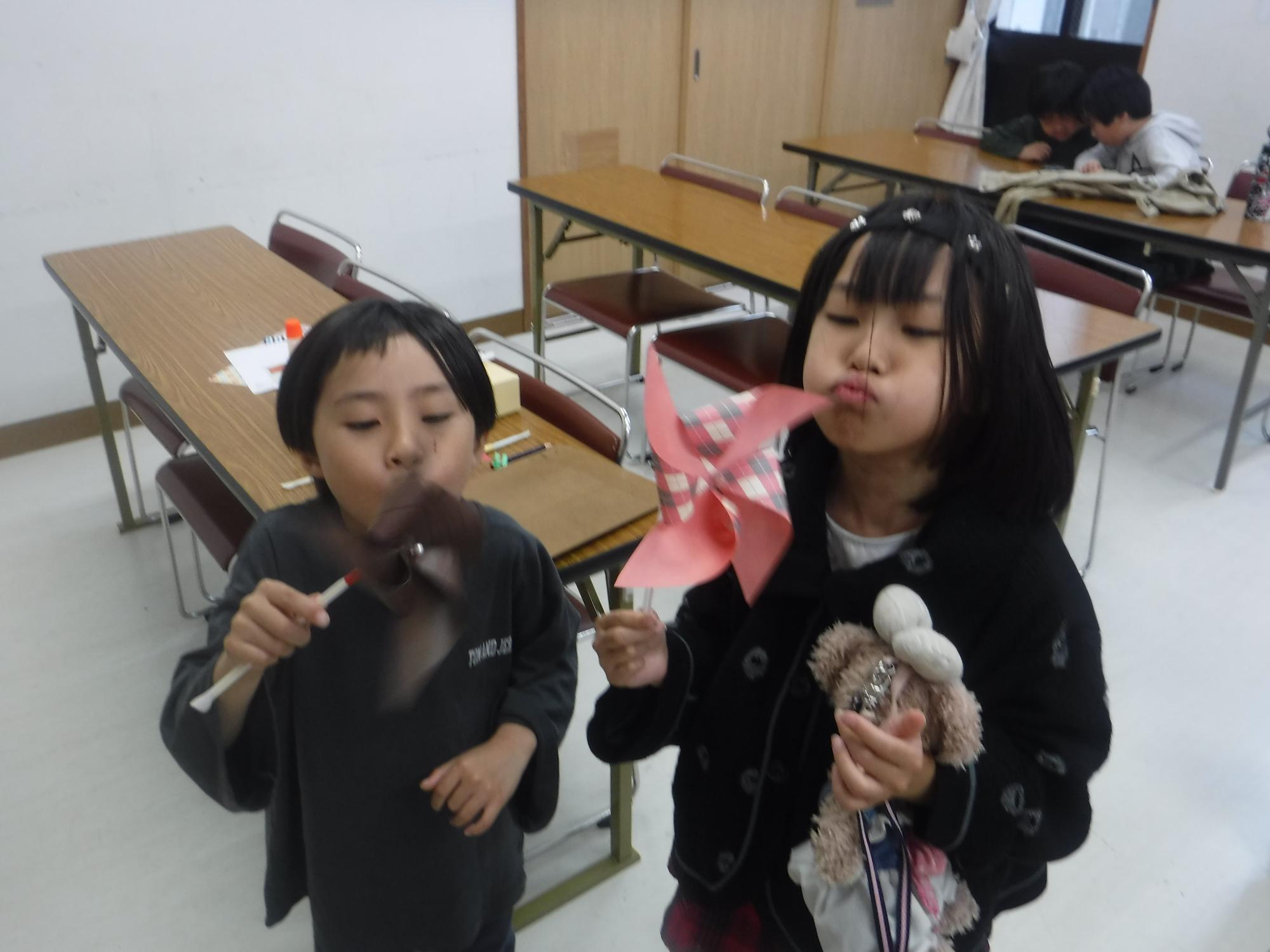 子どもたちがかざぐるまで遊んでいる写真