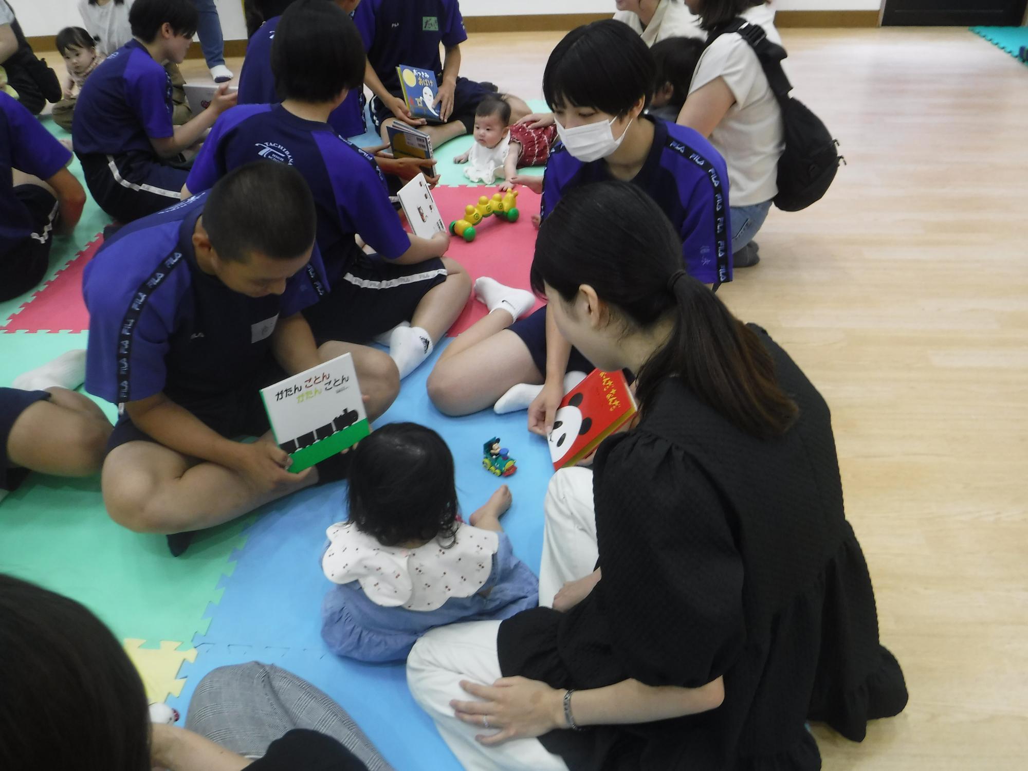 高校生が乳幼児親子に読み聞かせを行っている写真
