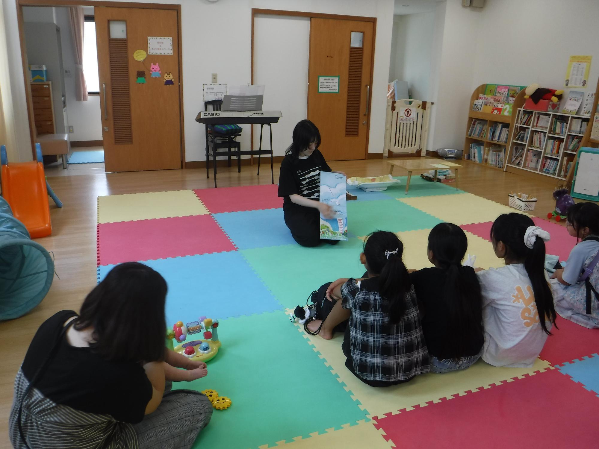 読み聞かせをしている大人と聞いている子どもたちの写真