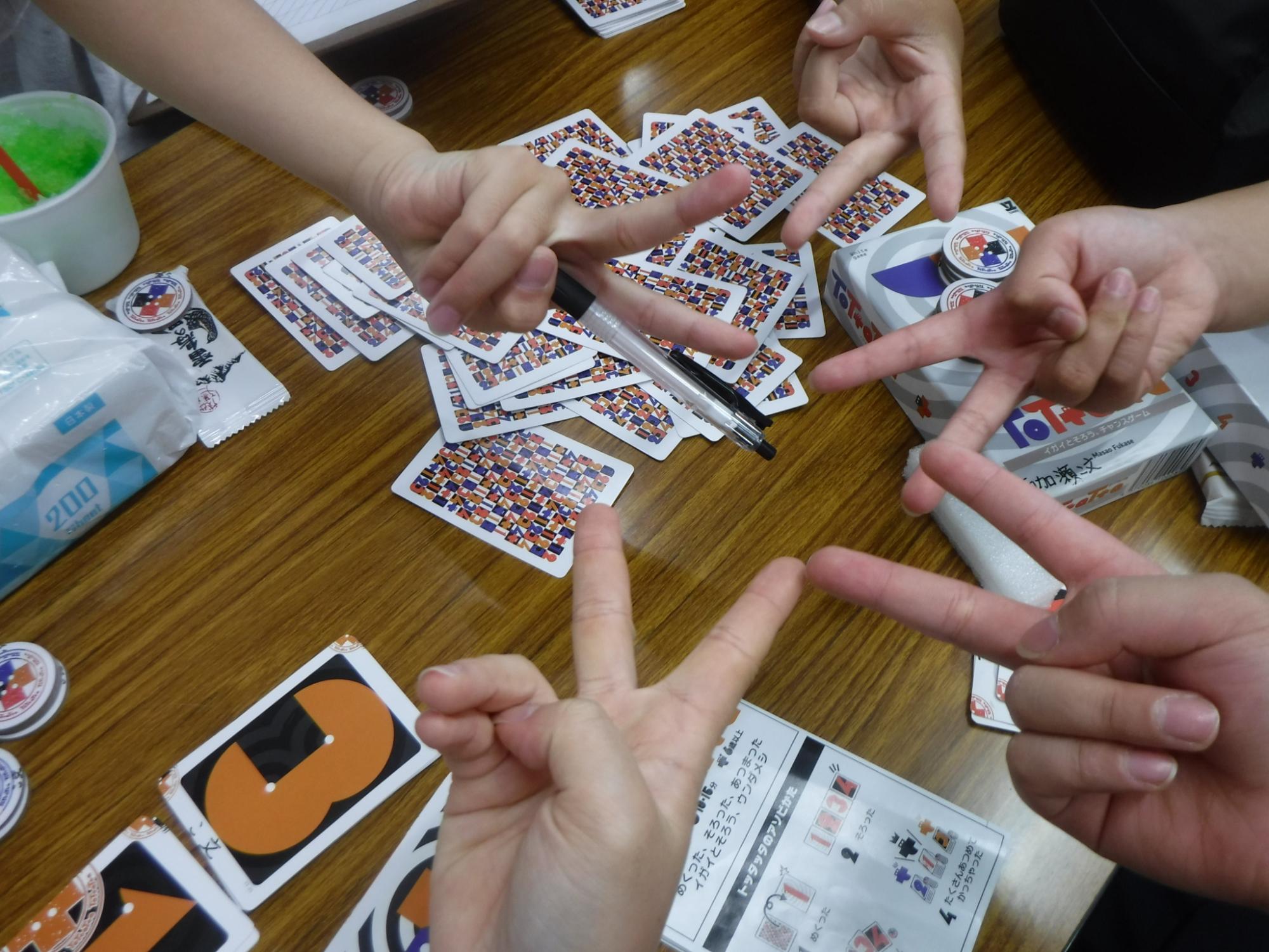 大学生とカードゲームをしてピースをしている様子