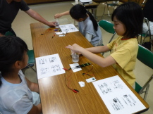 子供が資料を見て、コップに指を入れている写真