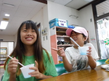 女の子2人が長机に座ってかき氷を食べている写真