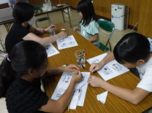 子供たちが机の上で、資料を見ながら配線を繋いでいる写真