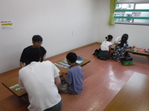 長机に対面で座って、ボードゲームをしている写真