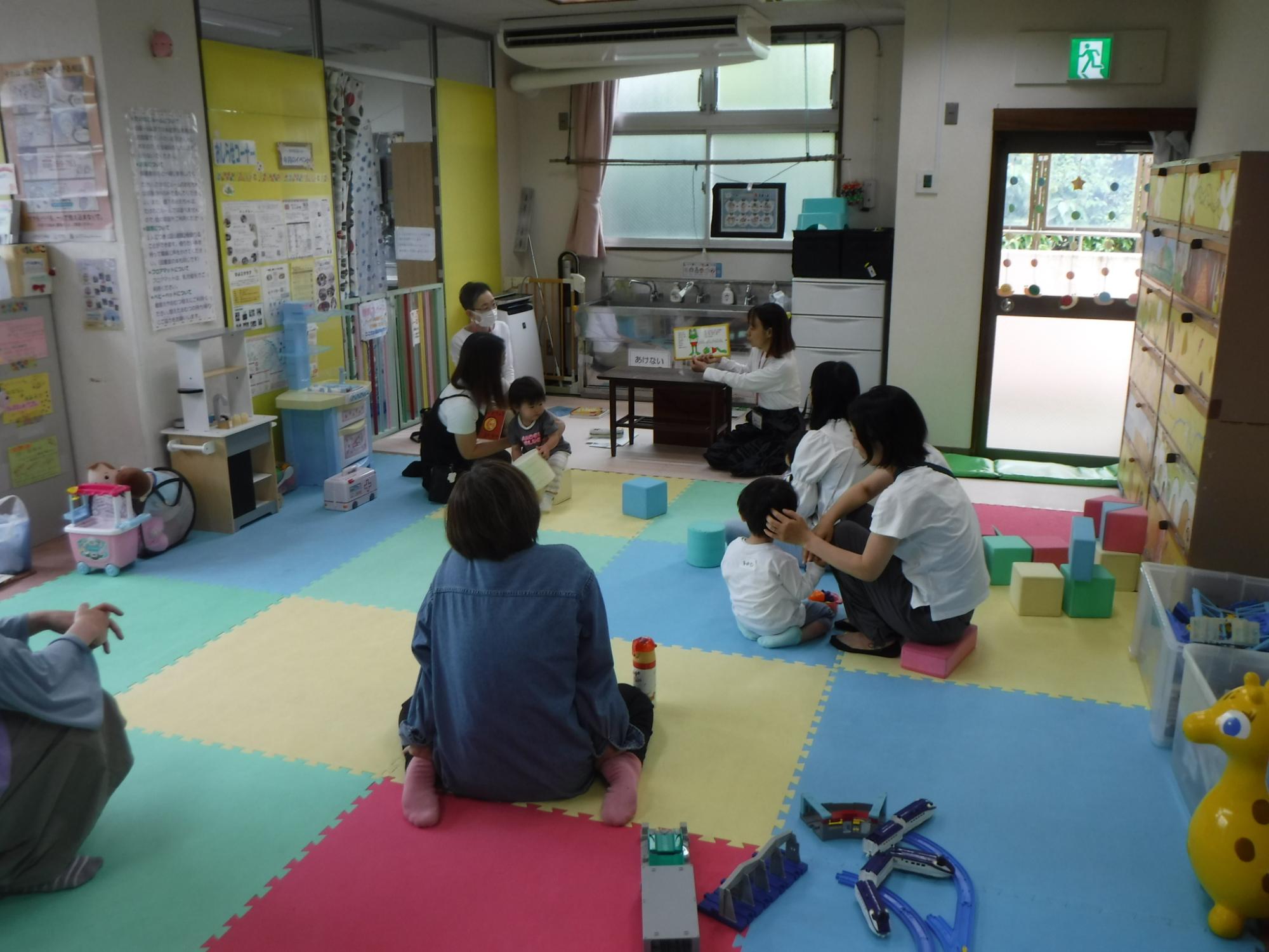 絵本を読んでいるスタッフと聞き入っている親子の様子
