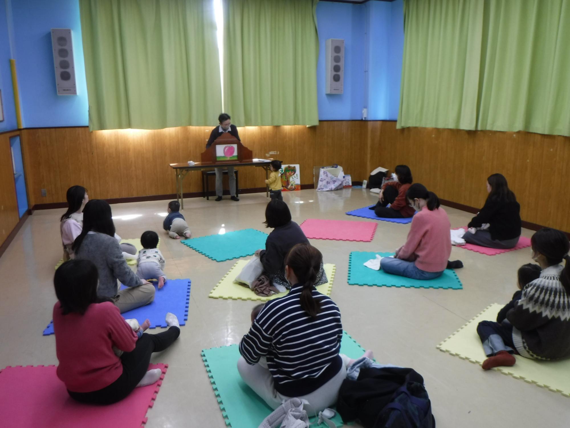 読み聞かせを聞いている幼児親子の写真