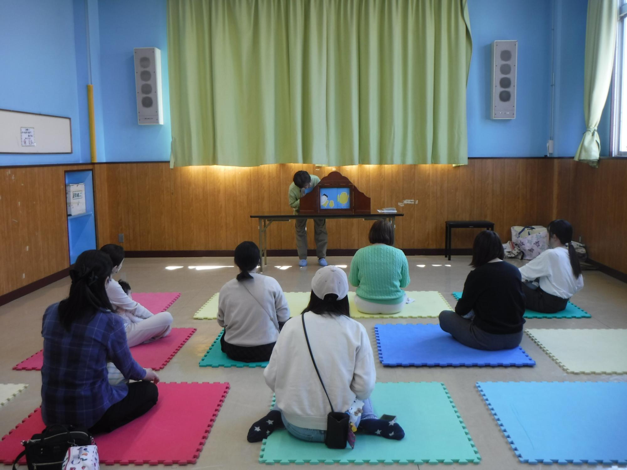 読み聞かせを聞いている幼児親子の写真