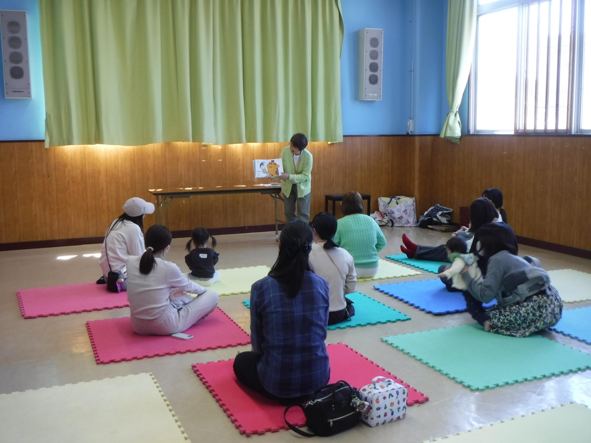 読み聞かせを聞いている幼児親子の写真