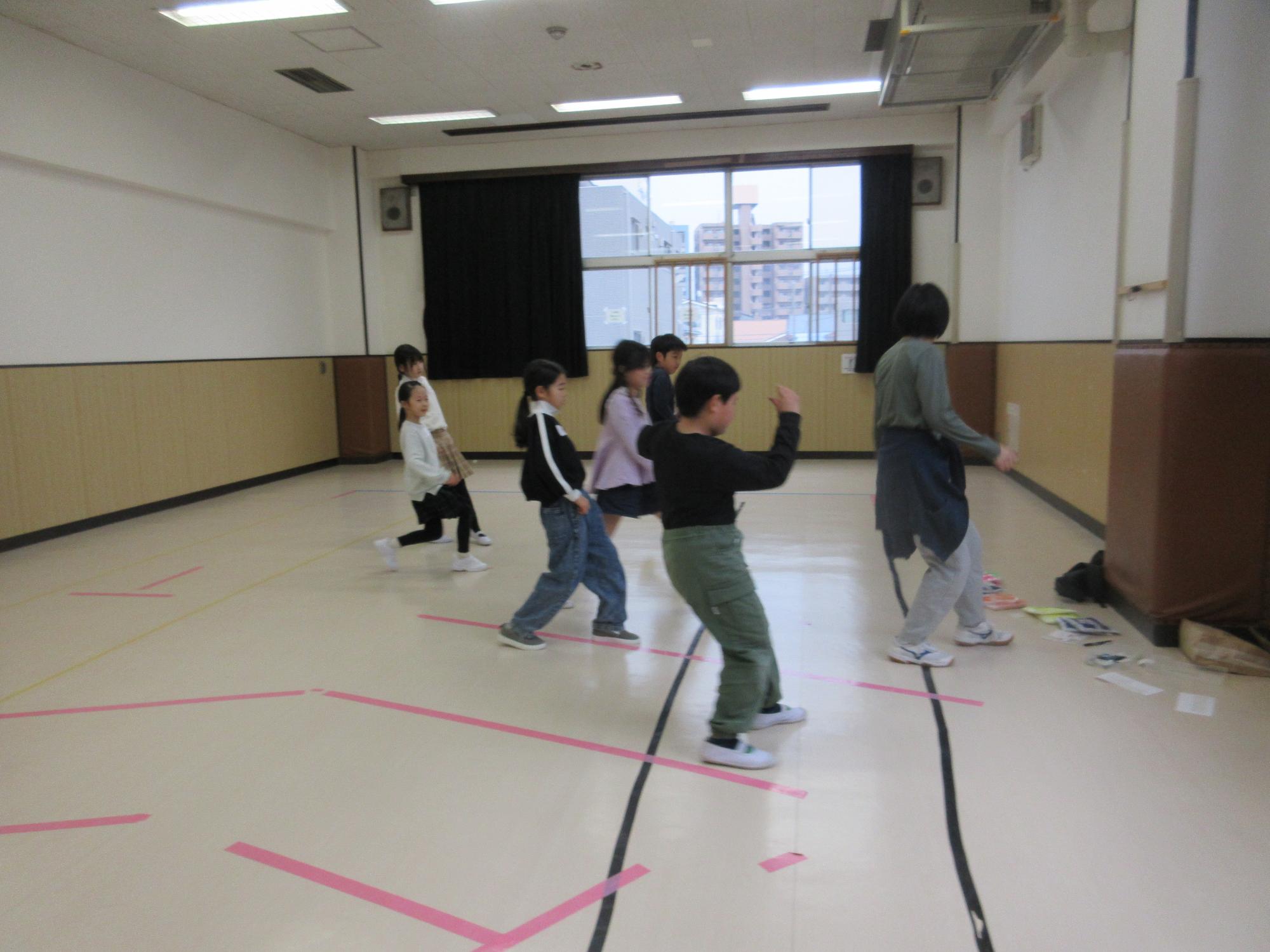 先生と一緒に、重心は後ろのまま前に一歩進むステップをする子どもたち