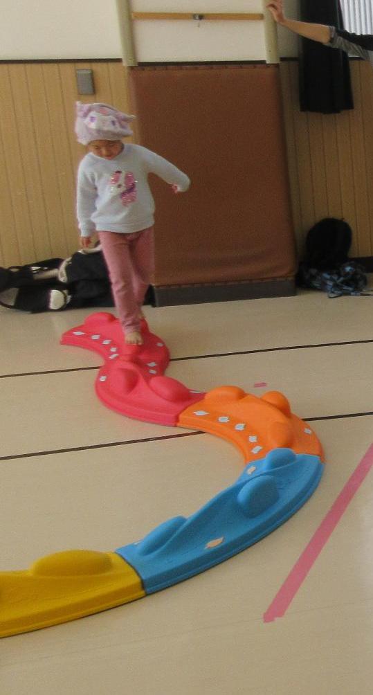 くねくね曲がった平均台の上を歩く幼児