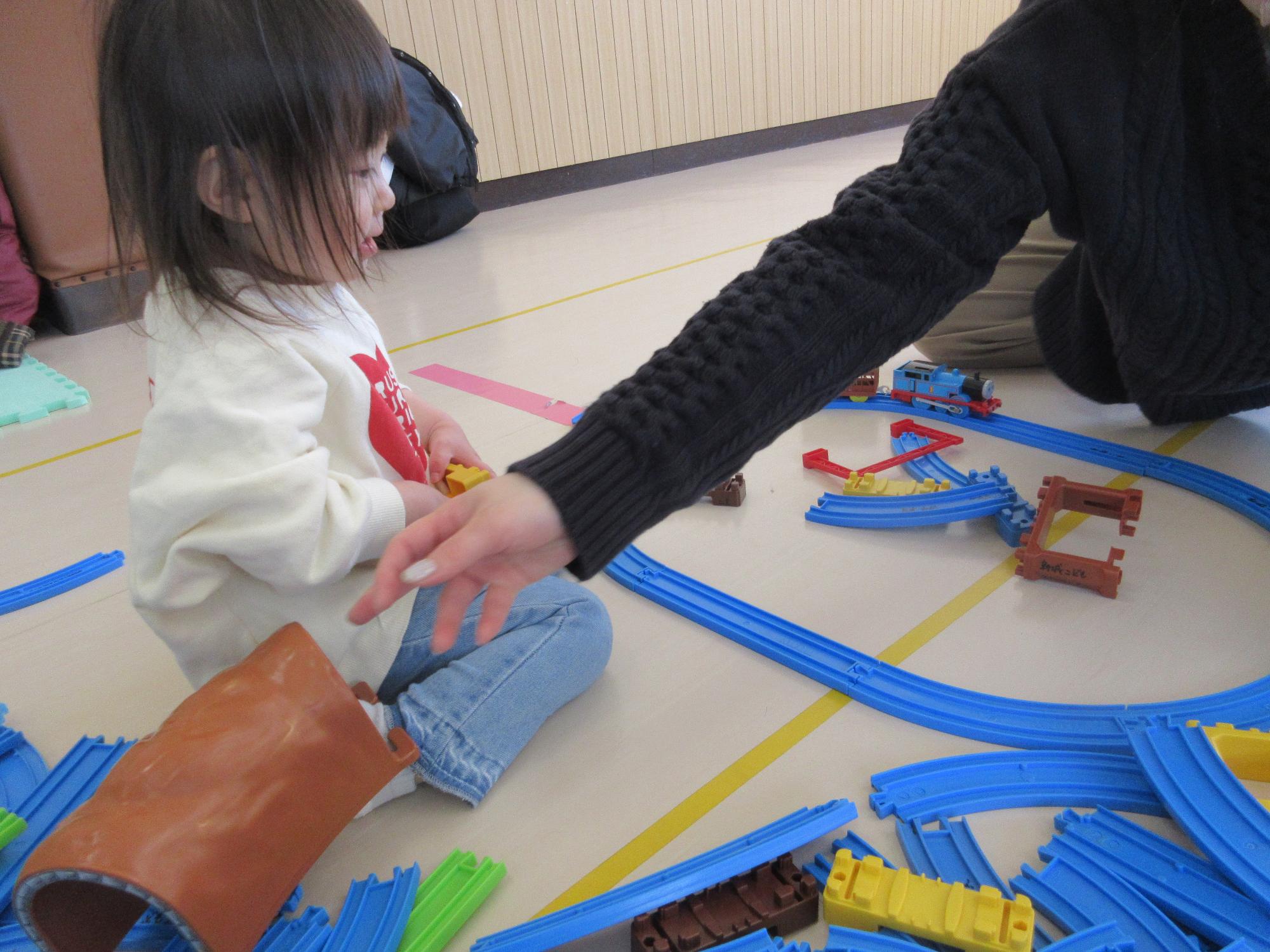 青いプラレールを組み立てる子ども