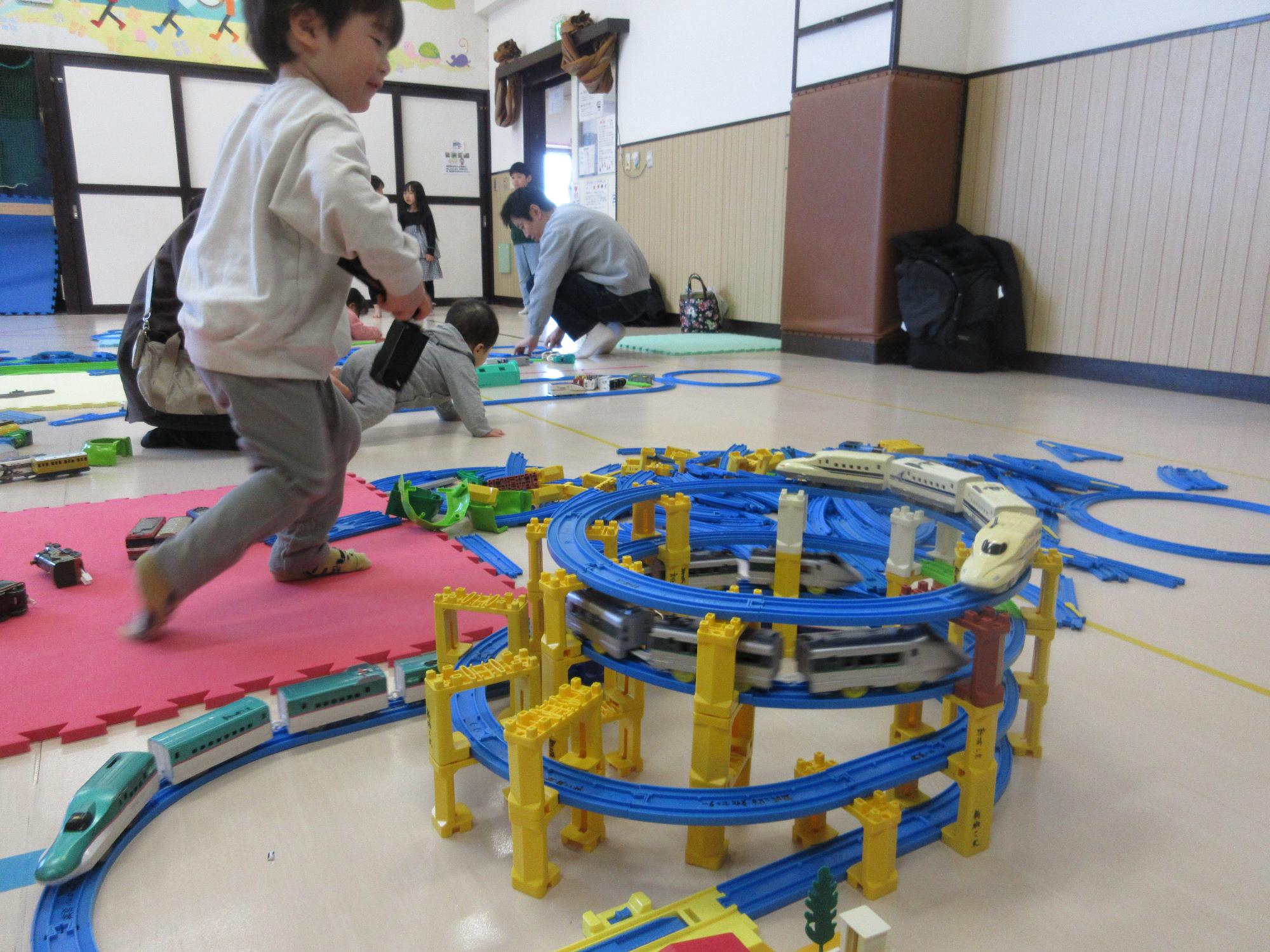 四段に組み立てられたプラレールで遊ぶ子ども