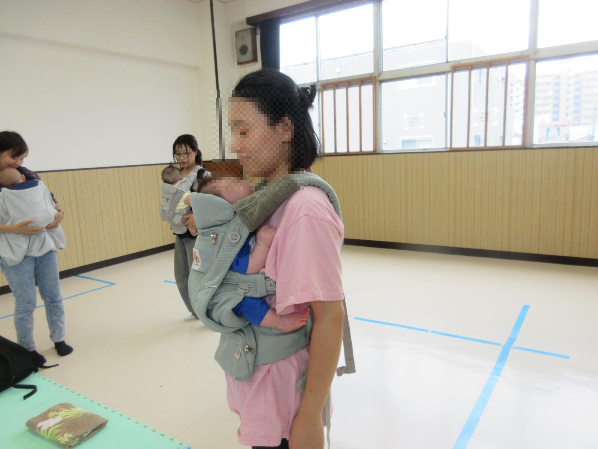 赤ちゃんを胸の前で抱っこ紐で抱っこするお母さん