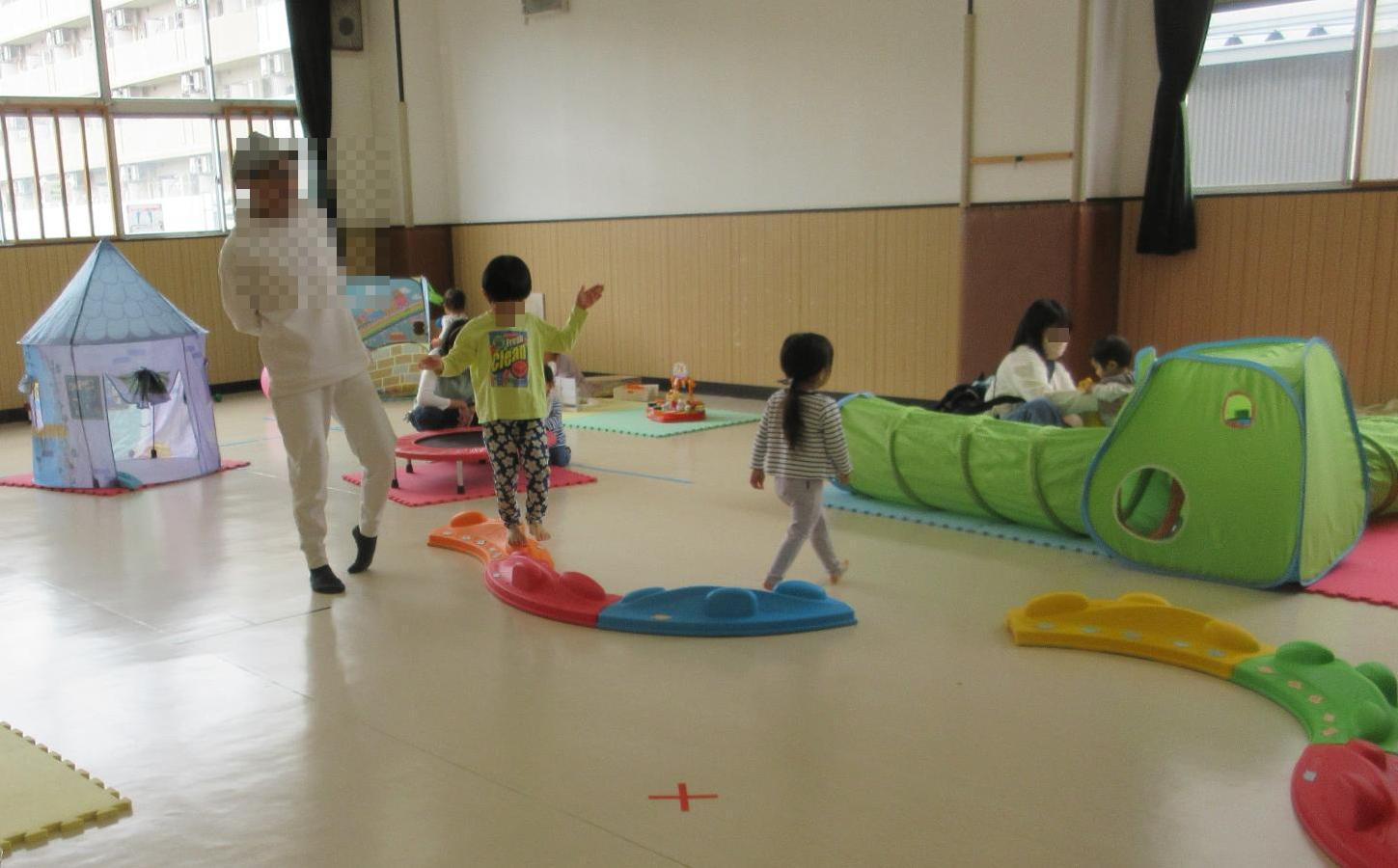 集会室で平均台を歩く子どもと見守るお父さん