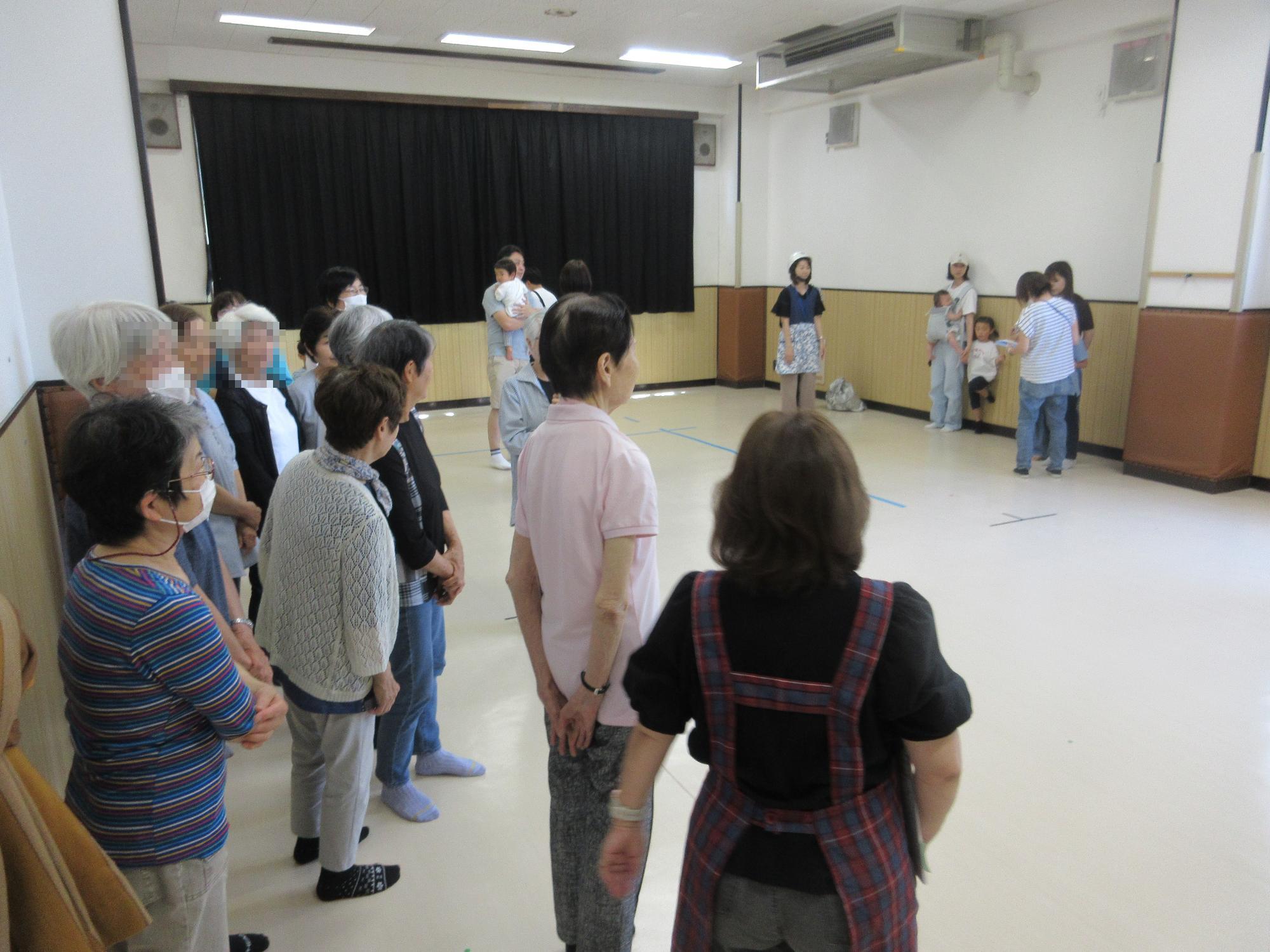集会室に利用者が立って集まり名前の確認を受けているところ