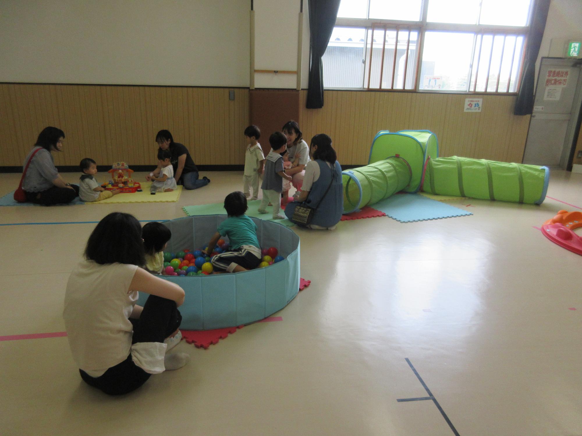 ボールプールで遊ぶ親子とお寿司屋さんのおもちゃで遊ぶ2組の親子とトンネルで遊ぶ2組の親子