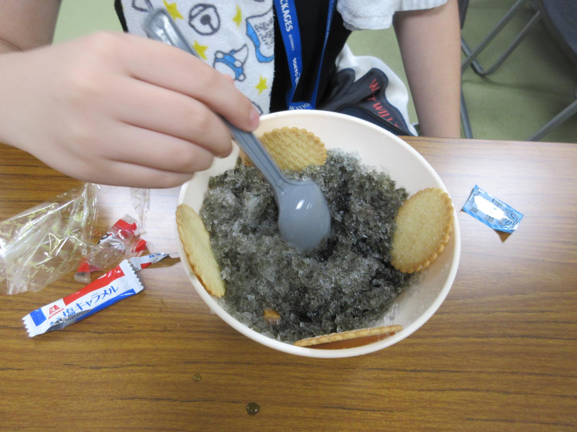 ドラキュラ味の黒いかき氷にビスケットやキャラメルやゼリーのトッピングをのせたもの