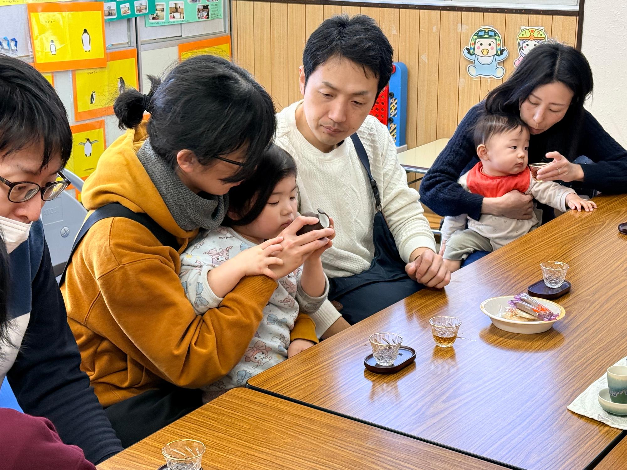 茶器からお茶の香りをかぐ親子