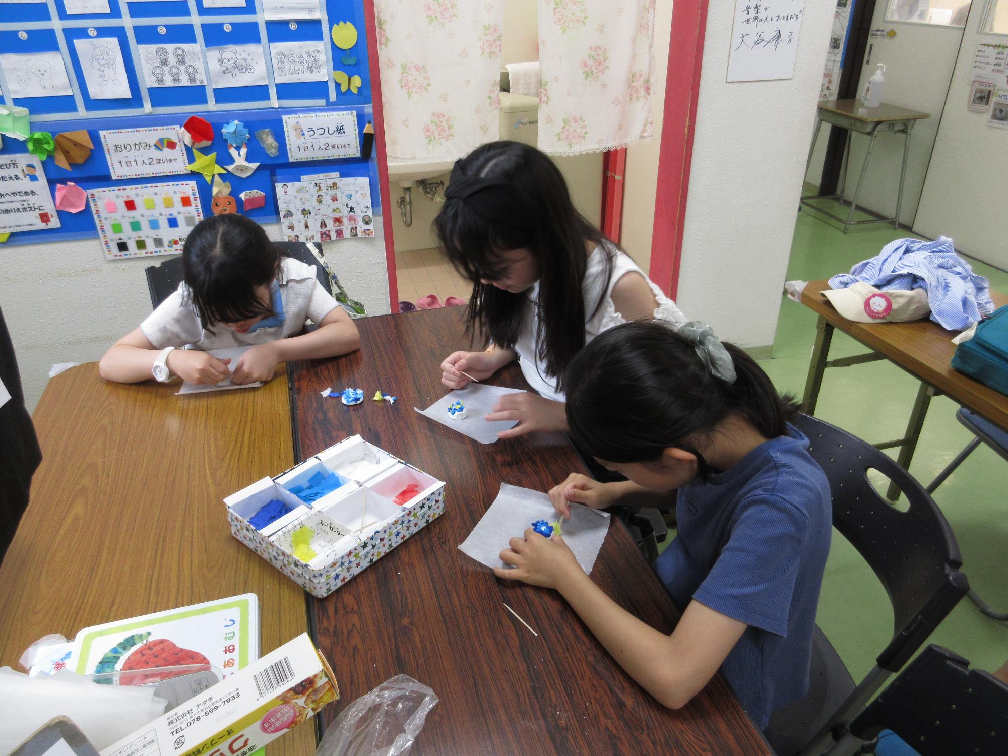 3人の子どもが真剣な表情でアジサイアートを作成している写真