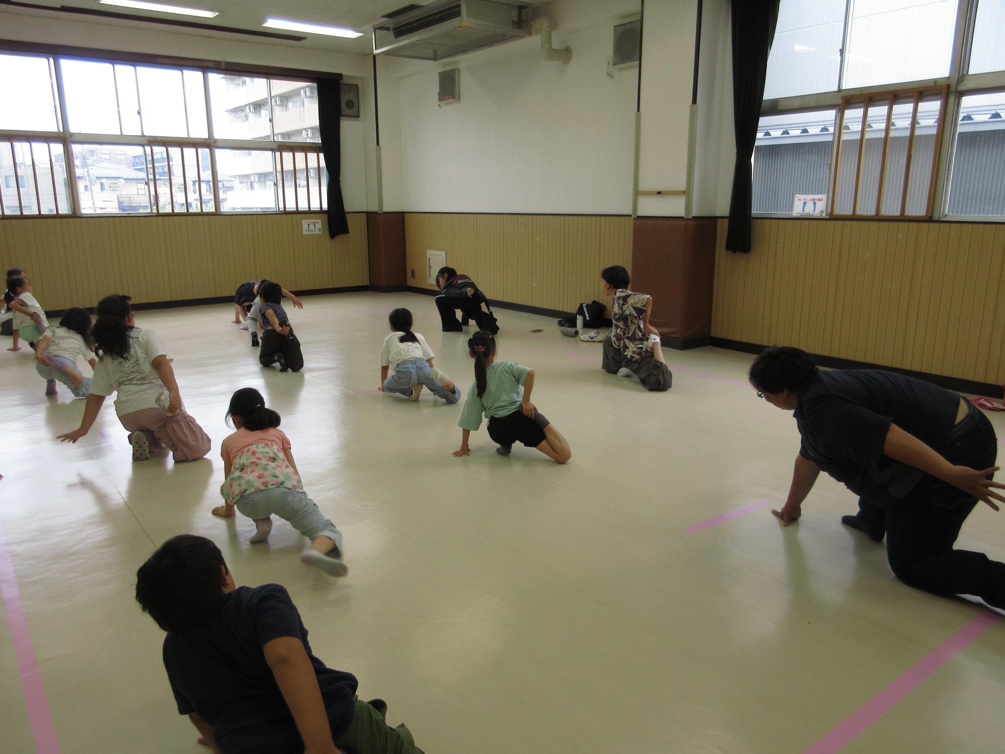 集会室で講師と子どもたちが柔軟をしている写真