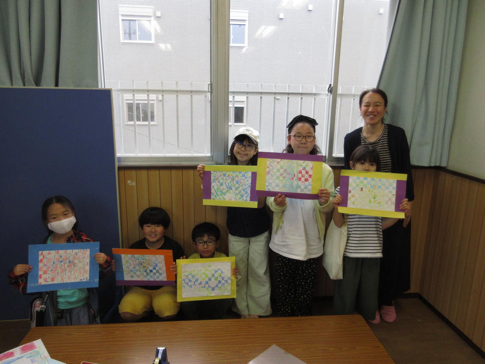 講師と6人の子どもがそれぞれの作品を持っている写真