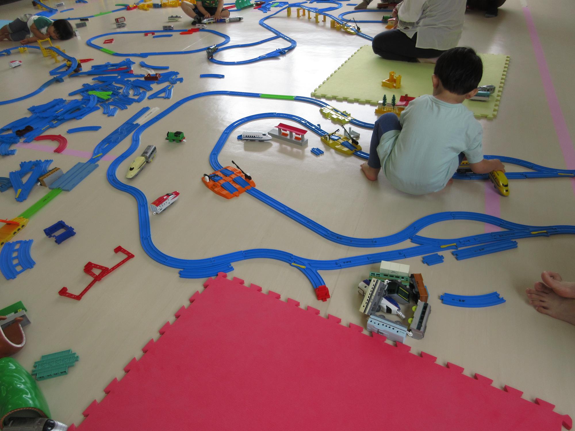 子どもが作ったレールで電車を走らせている写真