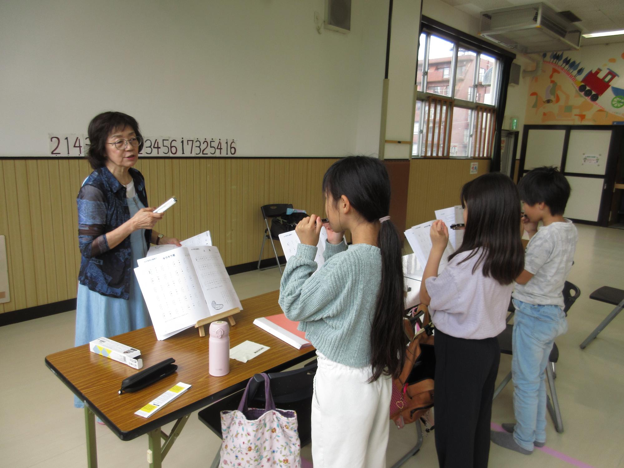 3人の子どもが講師に音階を教わっている写真