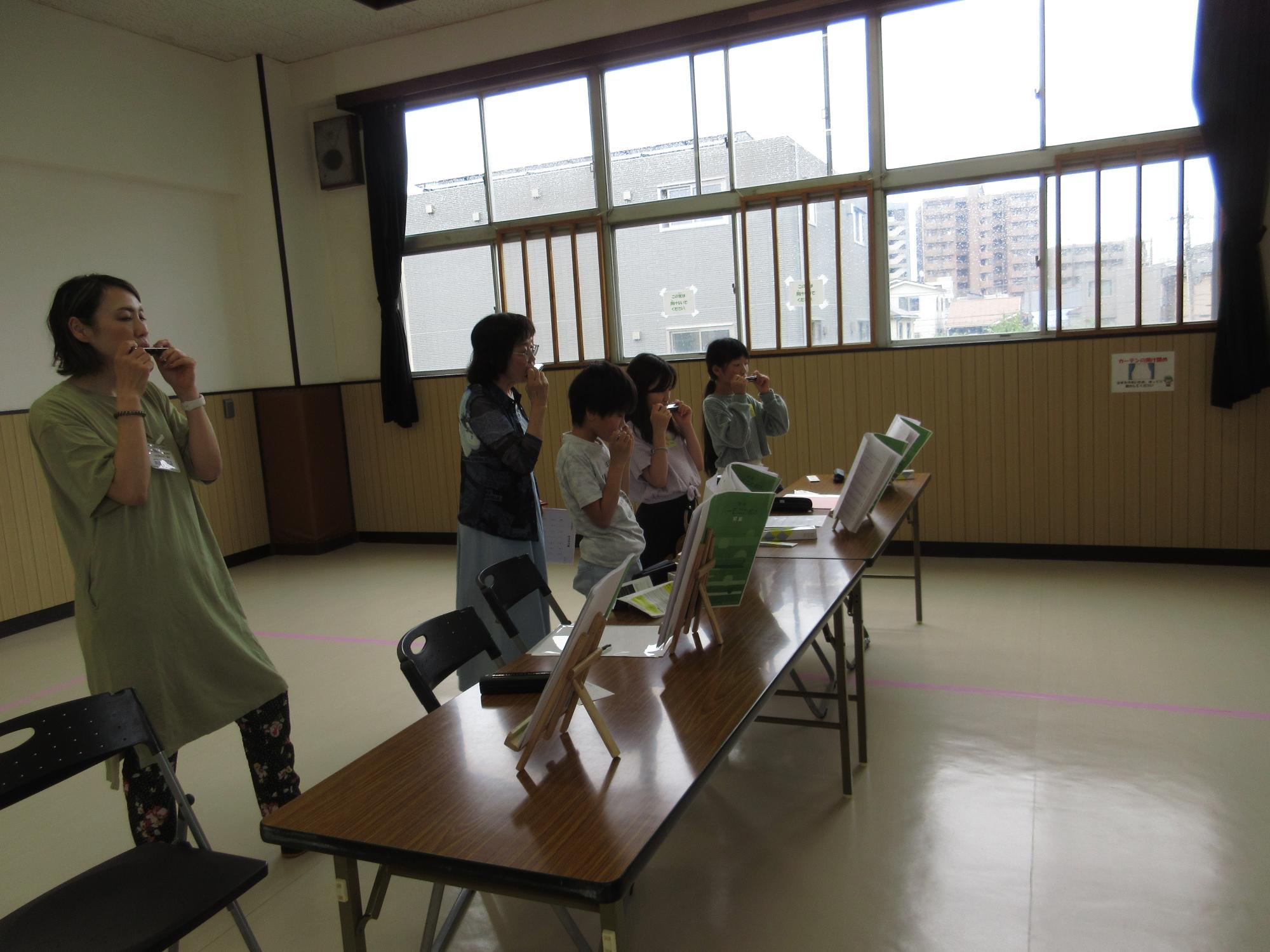 講師と4人の生徒が一緒にハーモニカを演奏している写真
