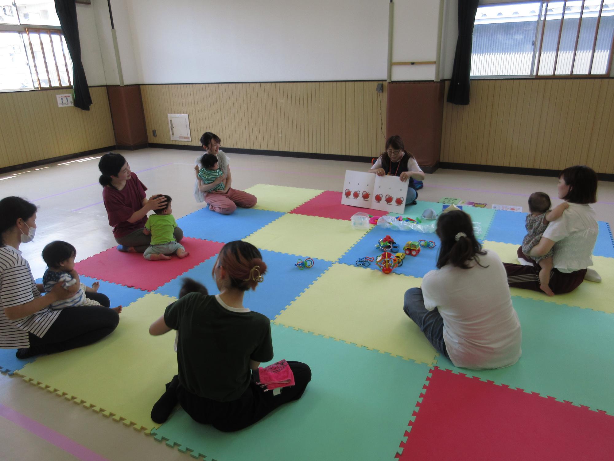 講師が6組の親子に絵本の読み聞かせをしている写真