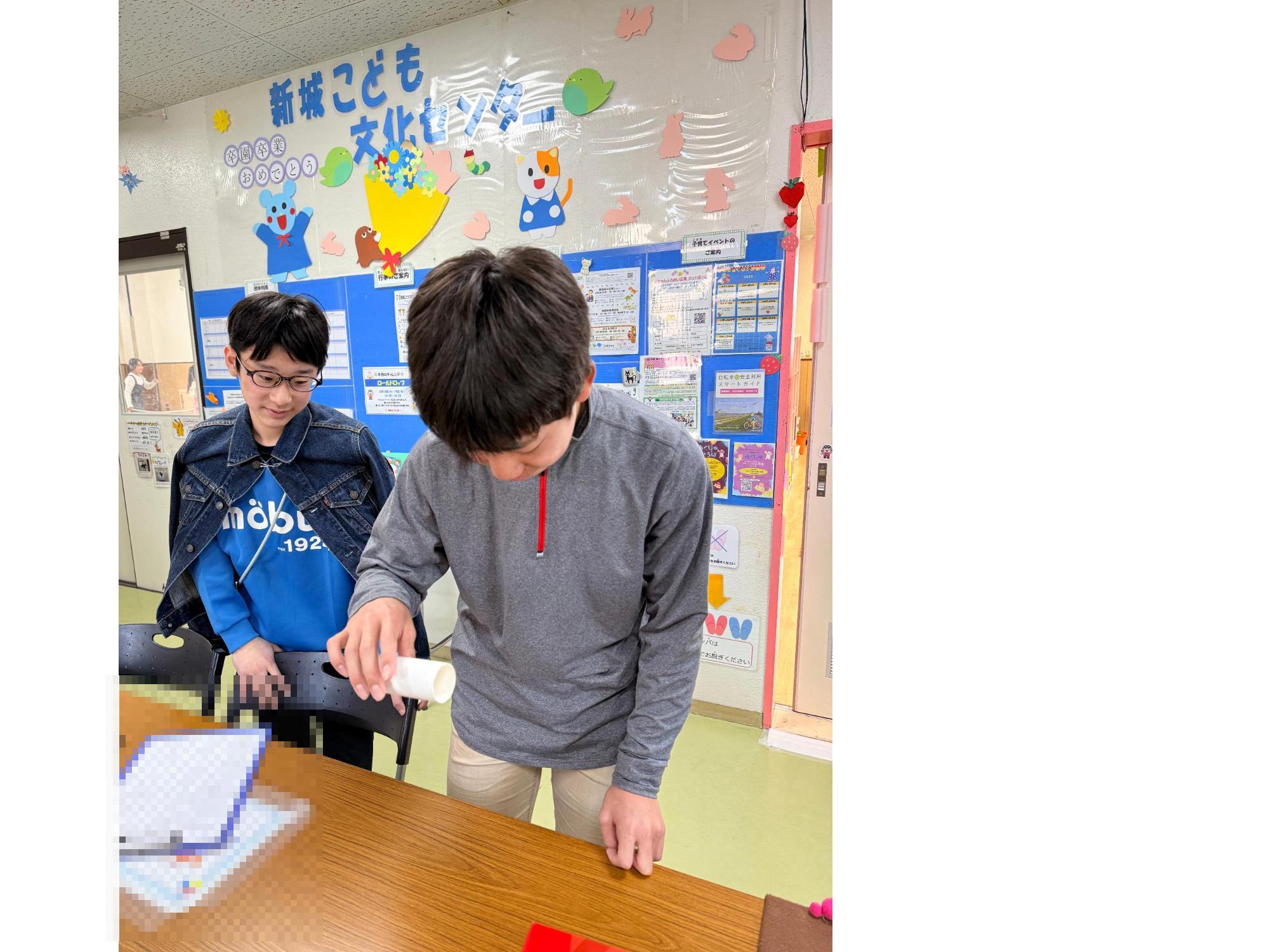トイレットペーパーの芯を水平に持ち落とす準備をするこども