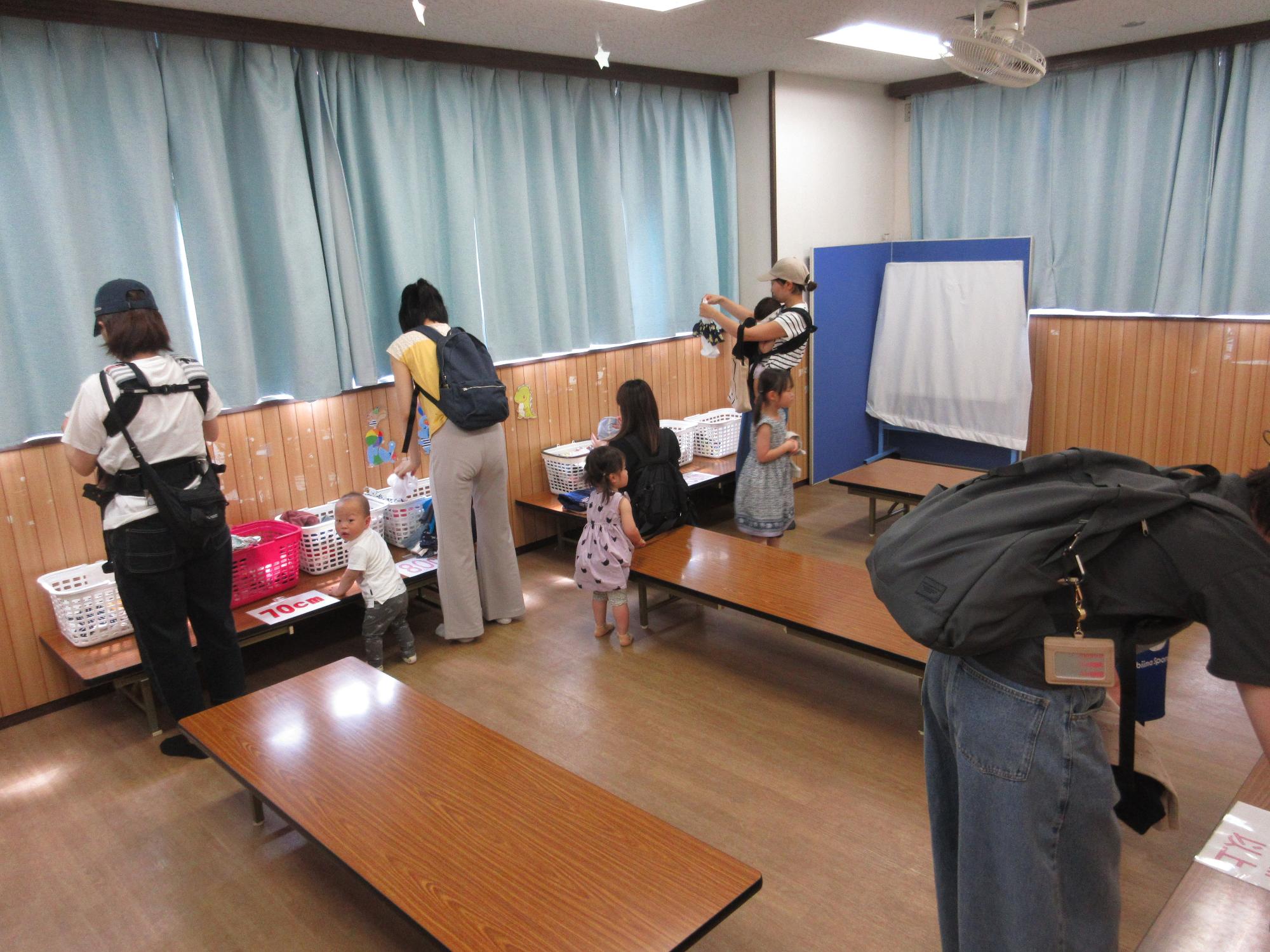 保護者の方が部屋に置かれたかごから洋服を選定している写真