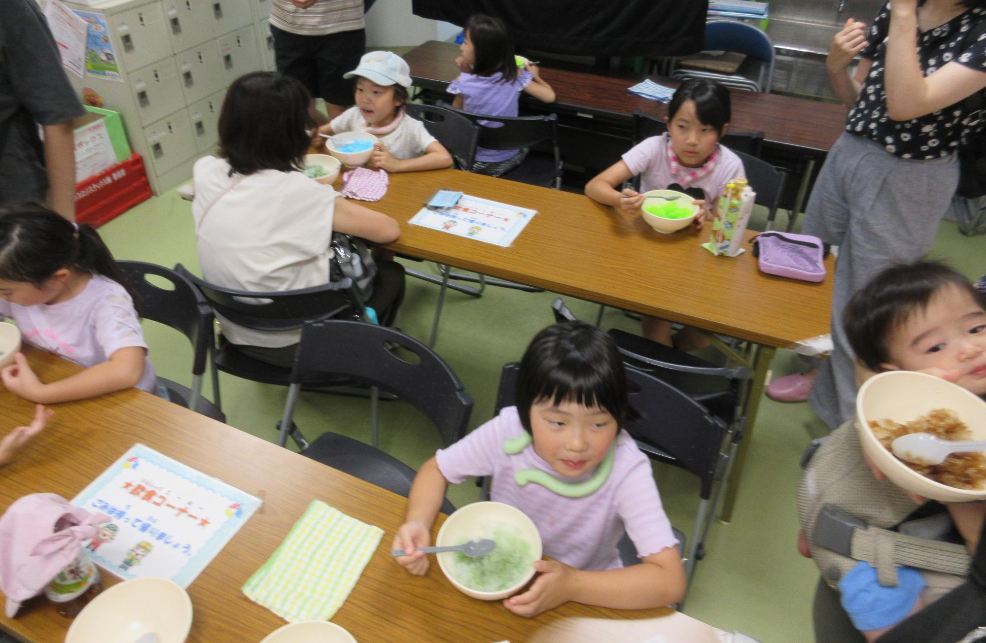 ブルーハワイ、コーラ、ドラキュラ味のかき氷を食べる子どもたち