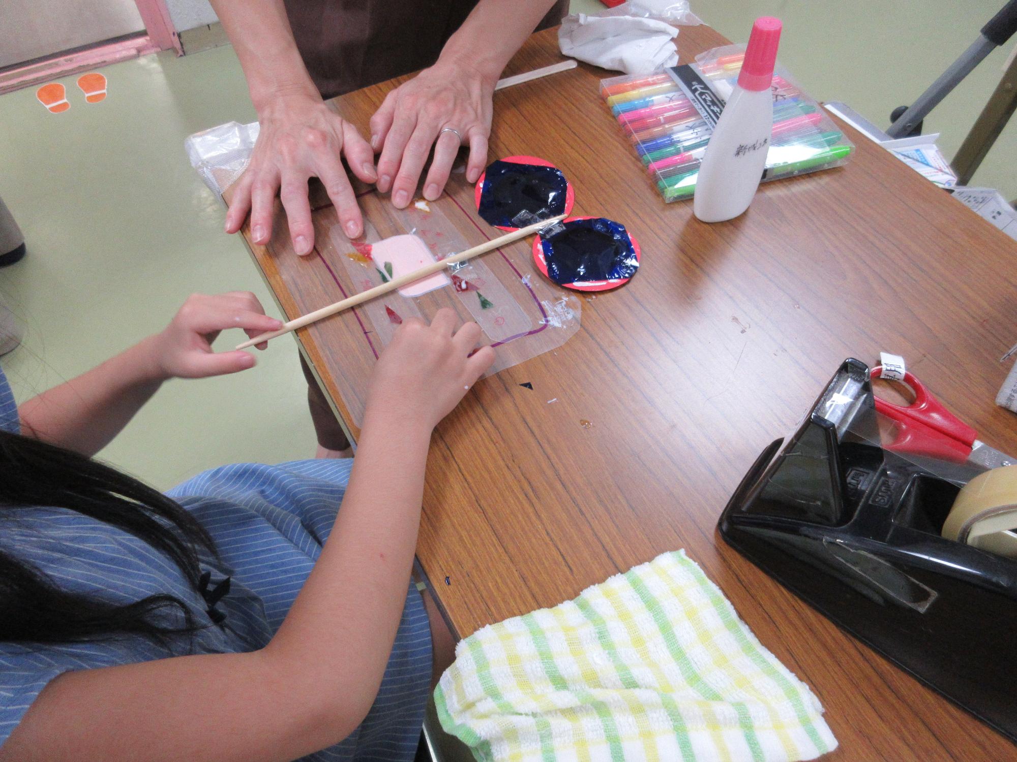 棒にメガネと羽をつけてとんぼのメガネをつくっています