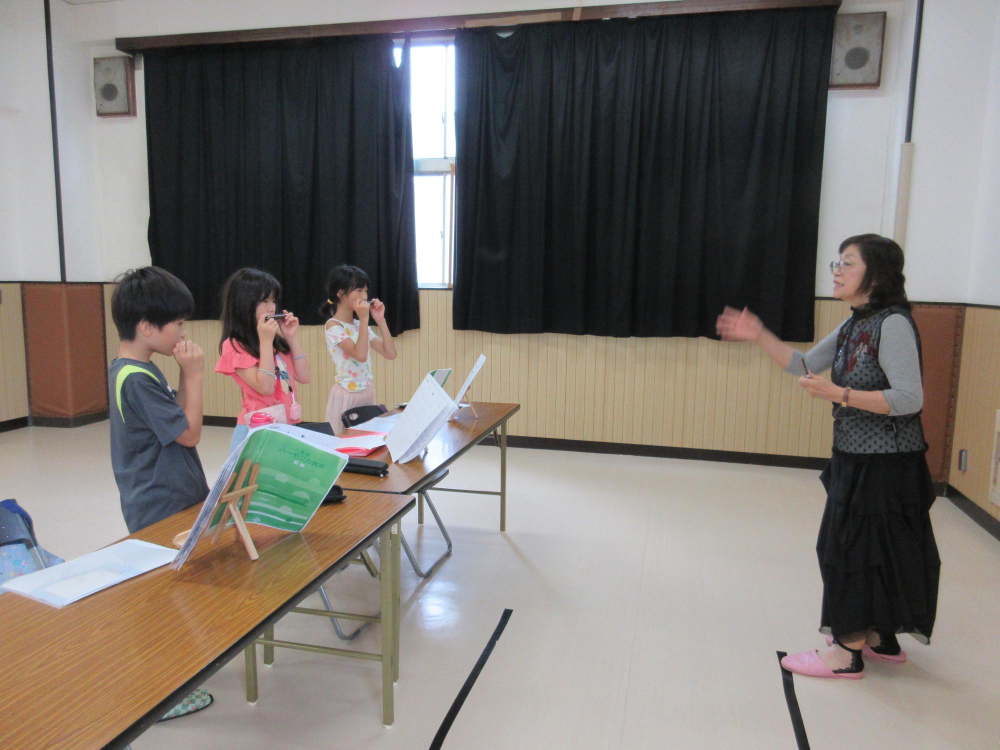 先生の指揮に合わせてハーモニカを吹く子どもたち