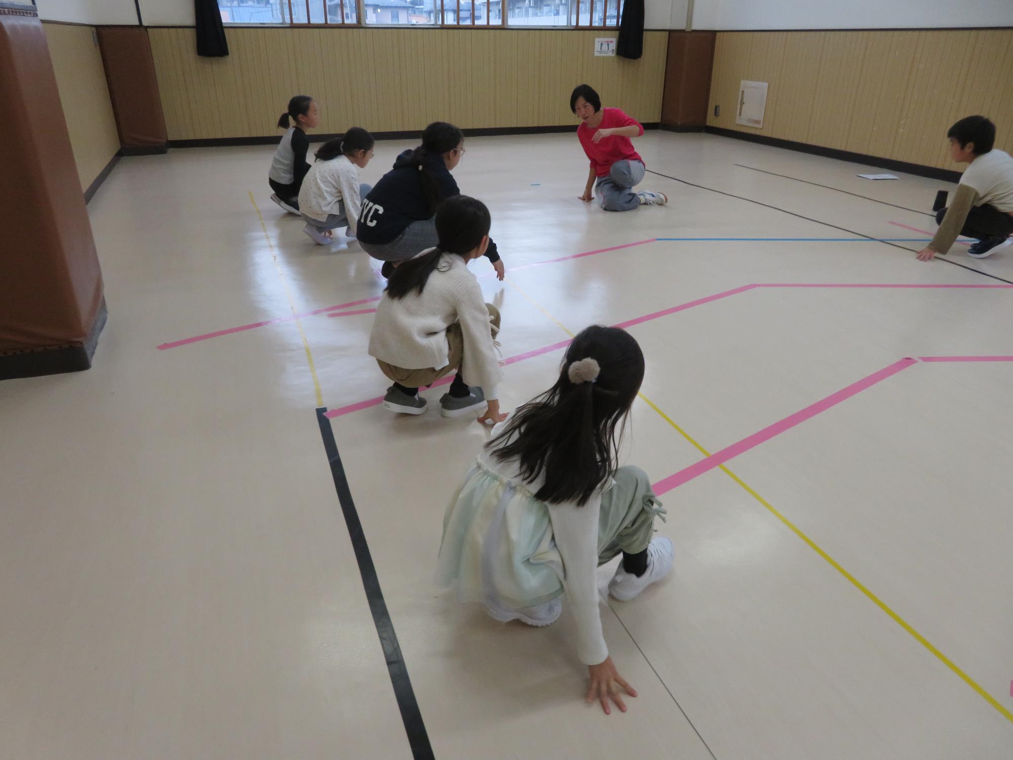 しゃがんだステップを練習する子ども達