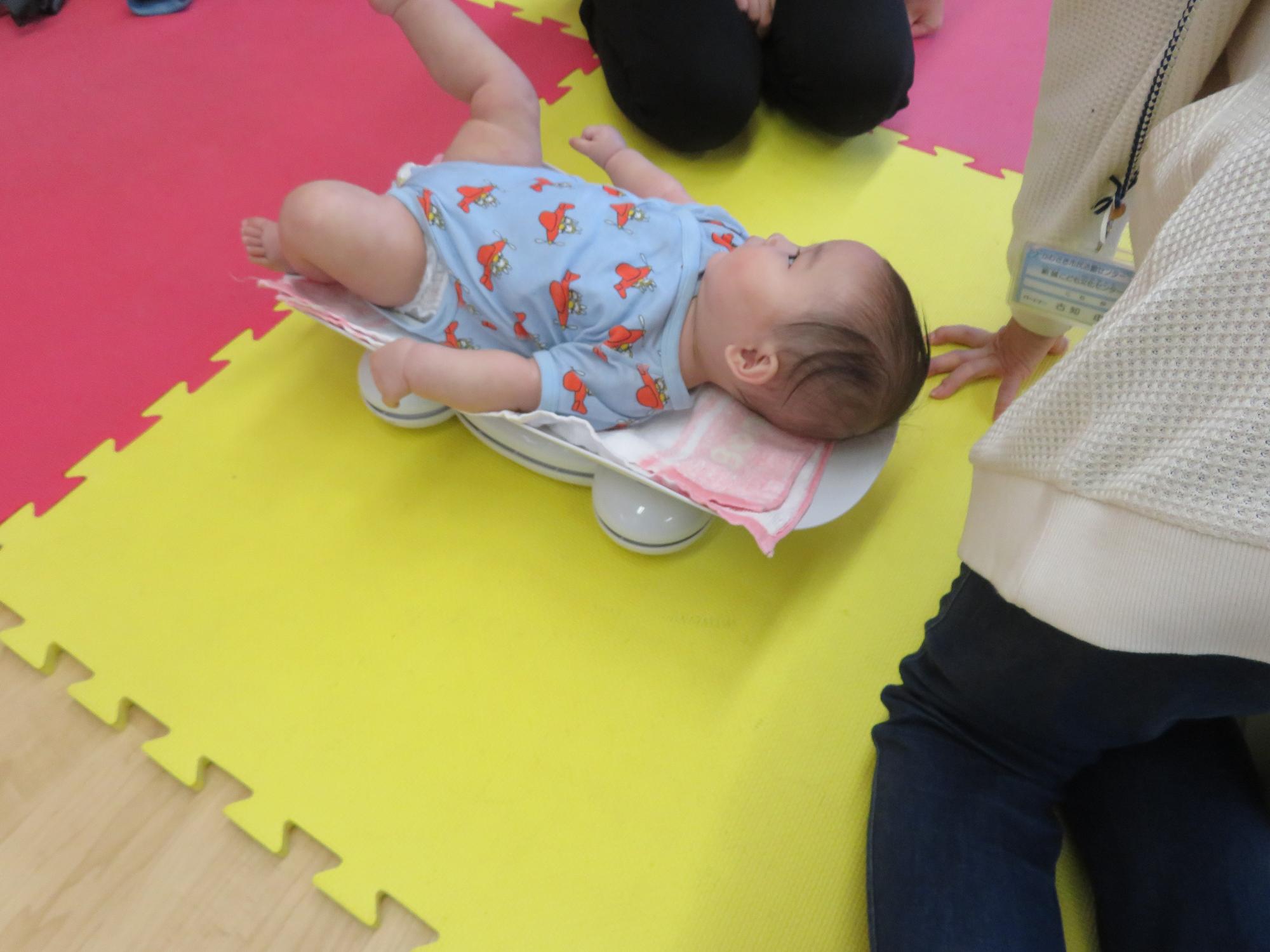 体重計に寝転ぶ乳児